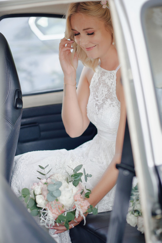 bride holding a bouquet sitting in the back of wedding car