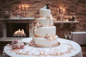 shows a multi layered, iced wedding cake beautifully presented on a decorated table