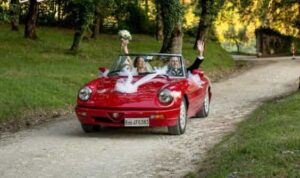 newly married couple arrive at reception venue in a red Alfa Romeo convertible