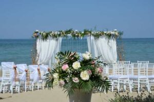 beach wedding ceremony with flowers decorating a canopy