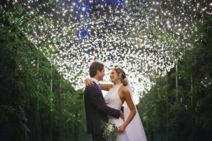 Bride and groom embrace under illuminated foliage canopy at wedding venue in Sorrento