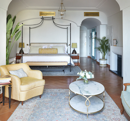 Italian luxury bedroom interior with tiled floor, wrought iron four poster bed and marble table