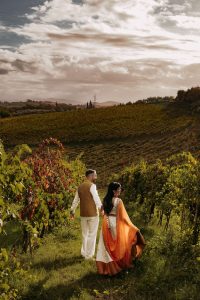 just married couple in Indian wedding clothes walking tgrough a vineyard