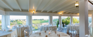 Covered dining terrace with views over vineyards, set up for a wedding banquet at a wedding villa in Italy.