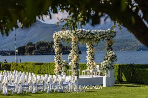 Indian wedding mandap decorated with white flowers on a lawn on the banks of Lake Maggiore in Italy.