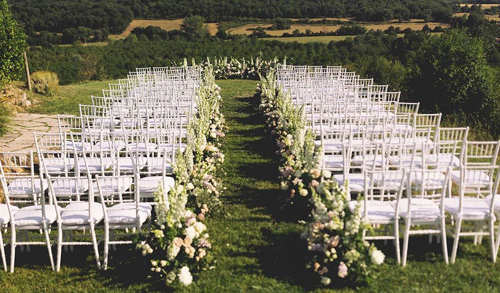Wedding ceremony set up outside in rural Tuscany with views of wooded hillsides.