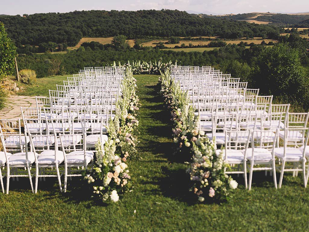 Wedding ceremony set up outside in rural Tuscany with views of wooded hillsides.